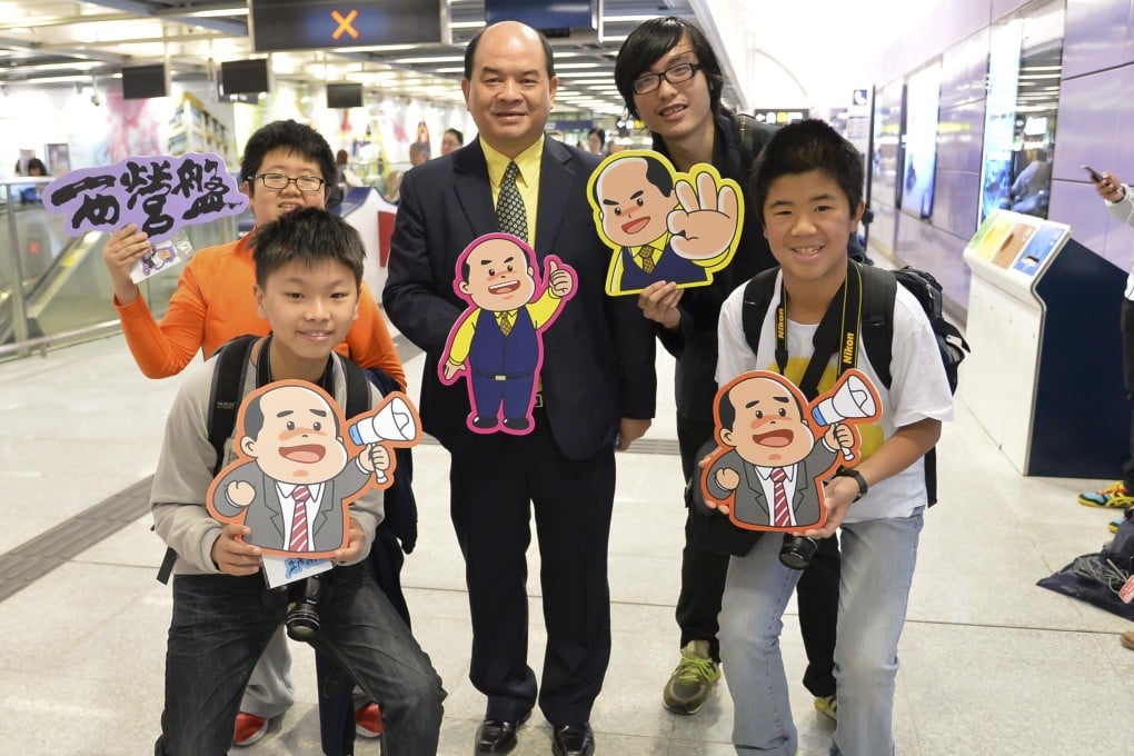 Francis Li (centre) with passengers wielding his cartoon likeness, at the opening of Sai Ying Pun station. Photo: Handout