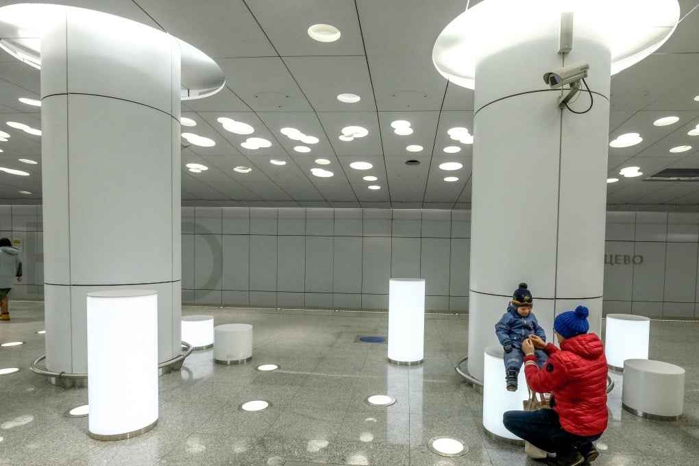 A woman and child waits for a train at the Solntsevo metro station in Moscow. Cylindrical white light boxes serve as seats. Photo: AFP