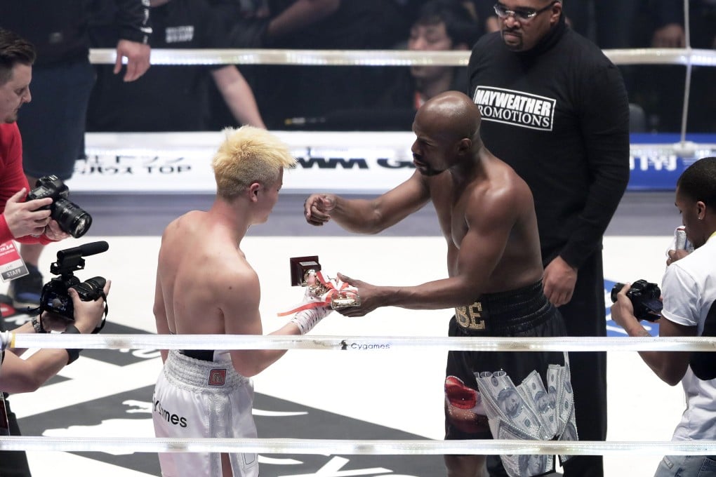 This is for you: Floyd Mayweather Jnr hands over his trophy to Japanese kickboxer Tenshin Nasukawa after his demolition job in Saitama. Photo: EPA
