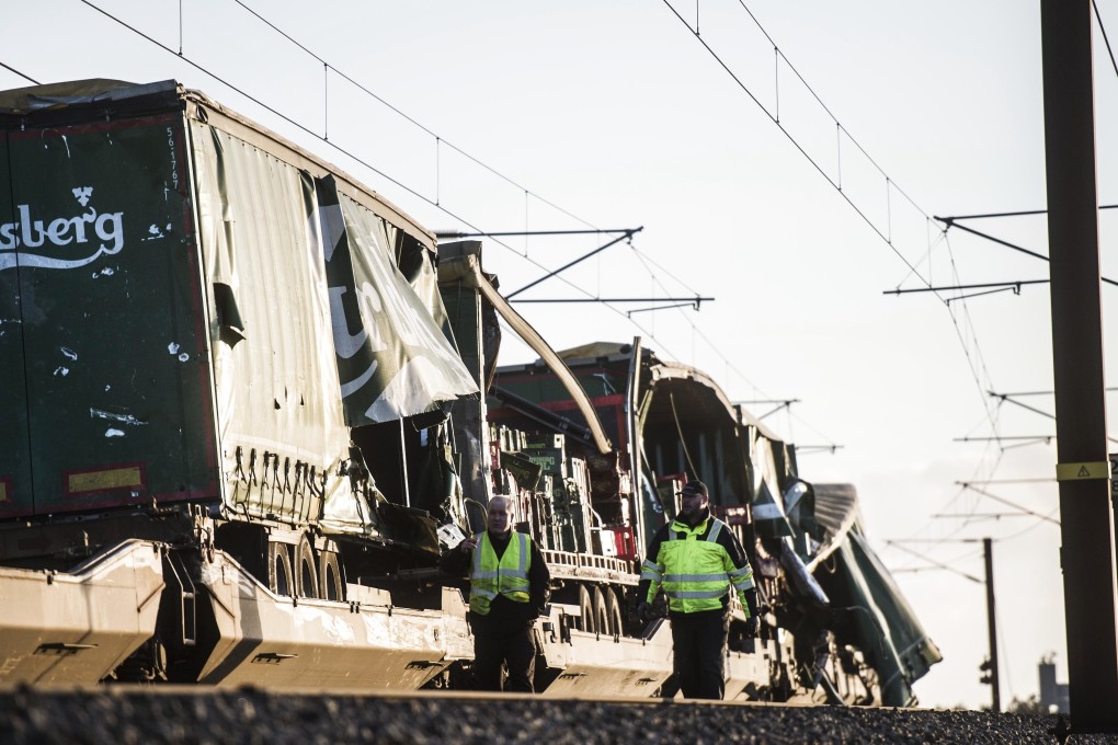 Two men walk past the damaged cargo train after the accident on January 2, 2019 in Nyborg, Denmark. Photo: AFP