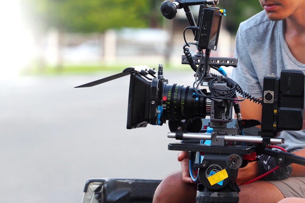 K7BTDG Behind the scenes of movie or video shooting production camera set and film crew at outdoor location. Photo: Alamy