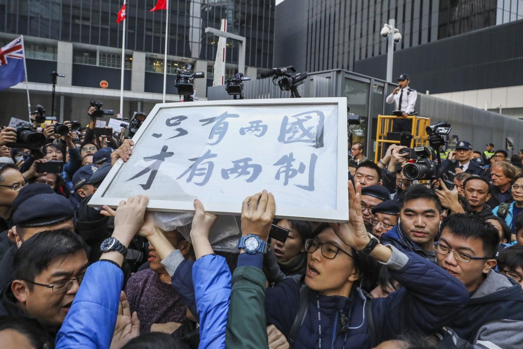 Security guards confront pro-independence protesters during the New Year's Day march in front of Hong Kong government headquarters in Tamar. Activists hold up a sign saying: ‘Only with two countries will there be two systems.’ Photo: Sam Tsang