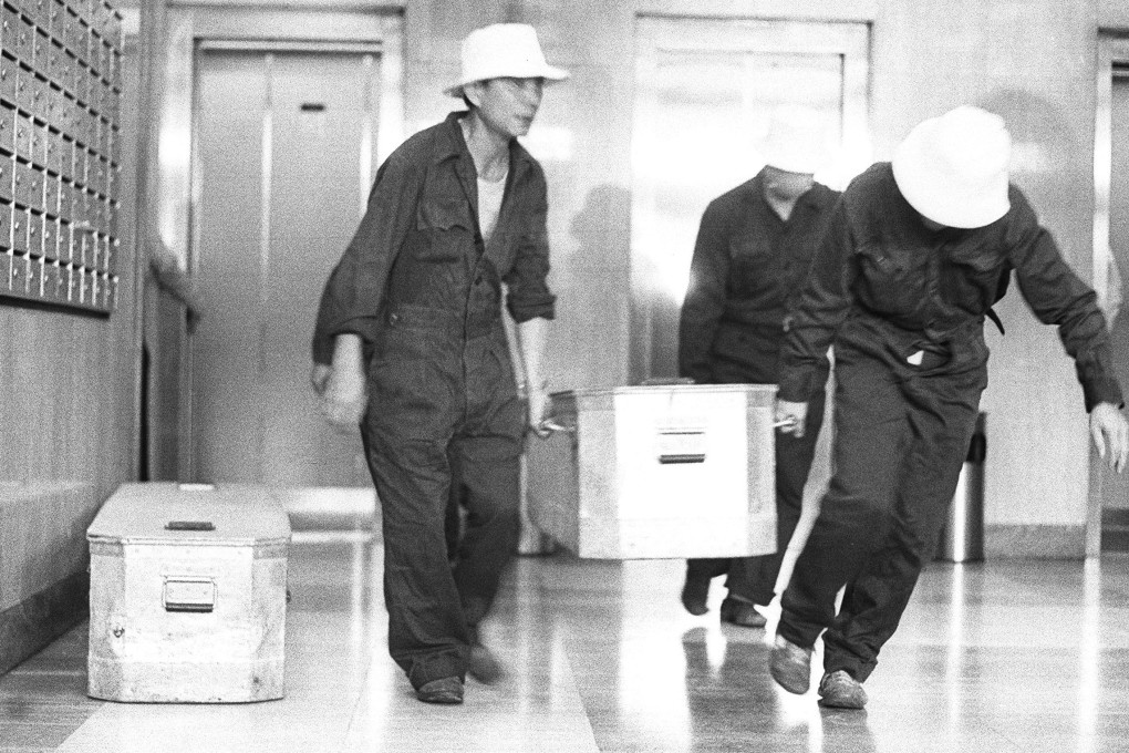 Mortuary staff putting one of the corpses into a temporary coffin. Two bodies were uncovered in a flower bed at Elizabeth House in 1984. Photo: Chan Kiu