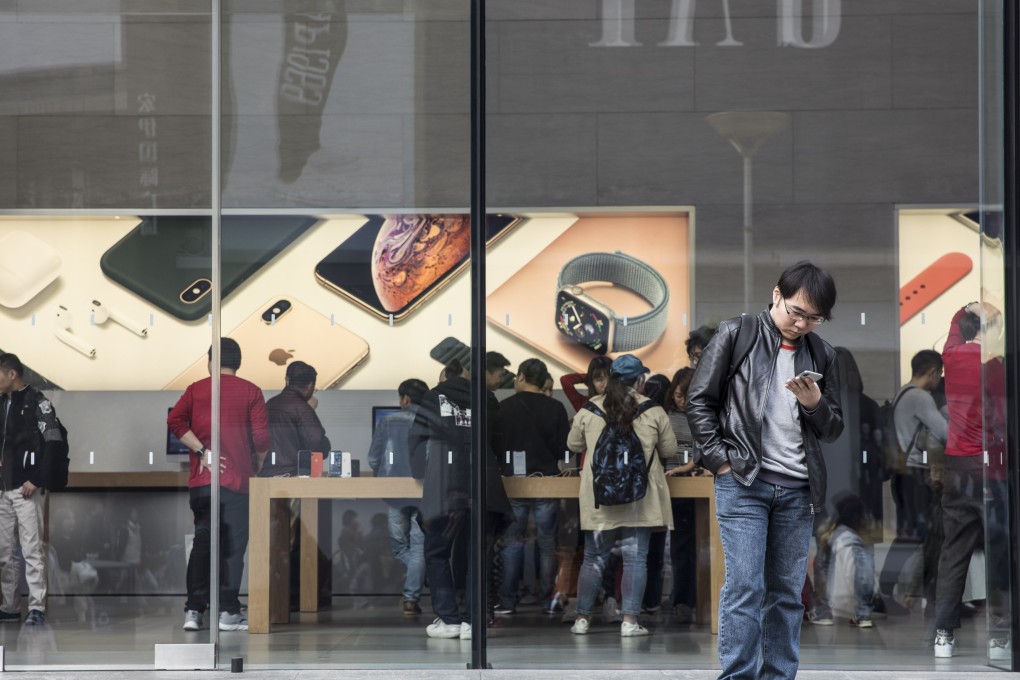 A man looks at his smartphone while standing in front of an Apple store in Shanghai on November 27, 2018. Photo: Bloomberg