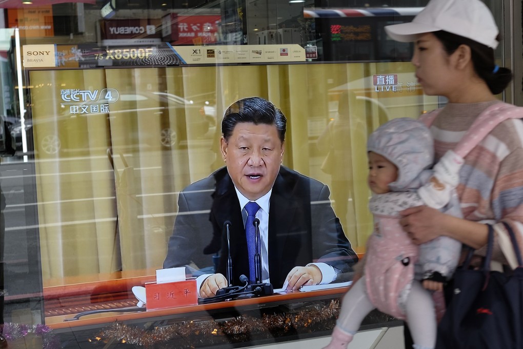 A mother carrying a child in New Taipei City walks past a televised speech by Chinese President Xi Jinping on January 2. Xi has said China will not abandon the use of military force to unify with Taiwan. Photo: AFP