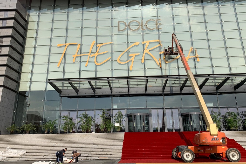 Workers remove the title of Dolce & Gabbana’s fashion show at the Shanghai Expo Centre on November 22, after the show was cancelled in the wake of a Chinese backlash against the fashion brand’s perceived racism. Photo: Reuters