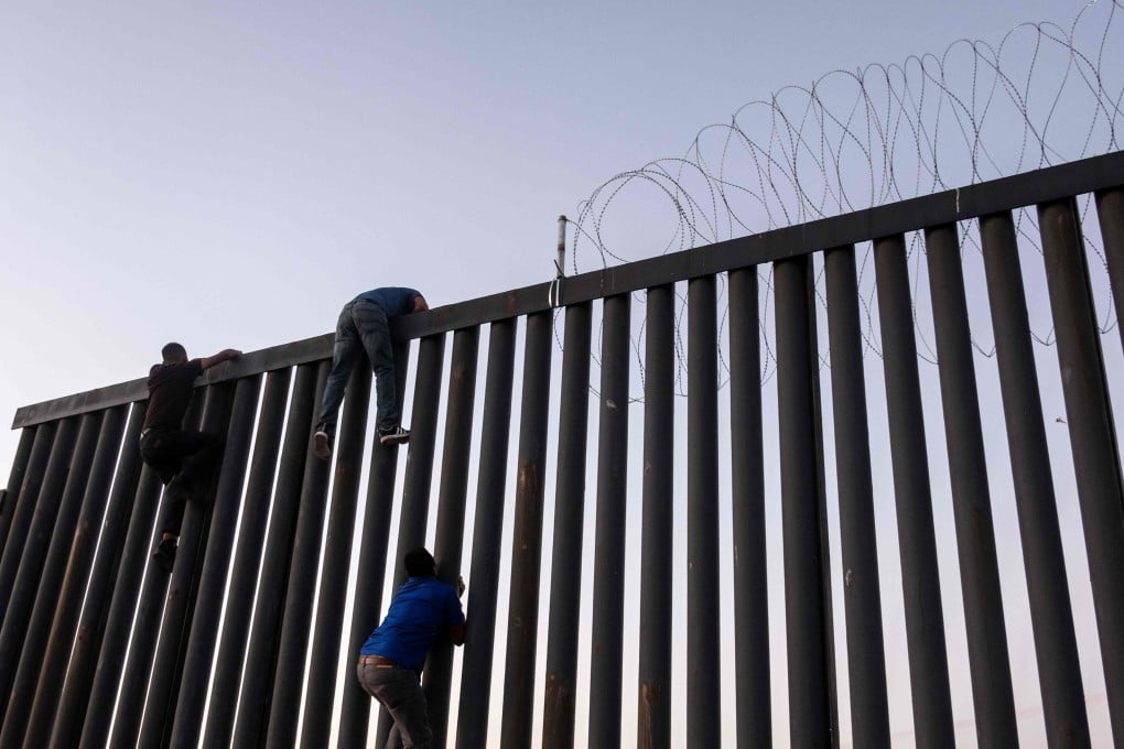 Men from Mexico climb the US-Mexico border wall in Playas de Tijuana. File photo: AFP