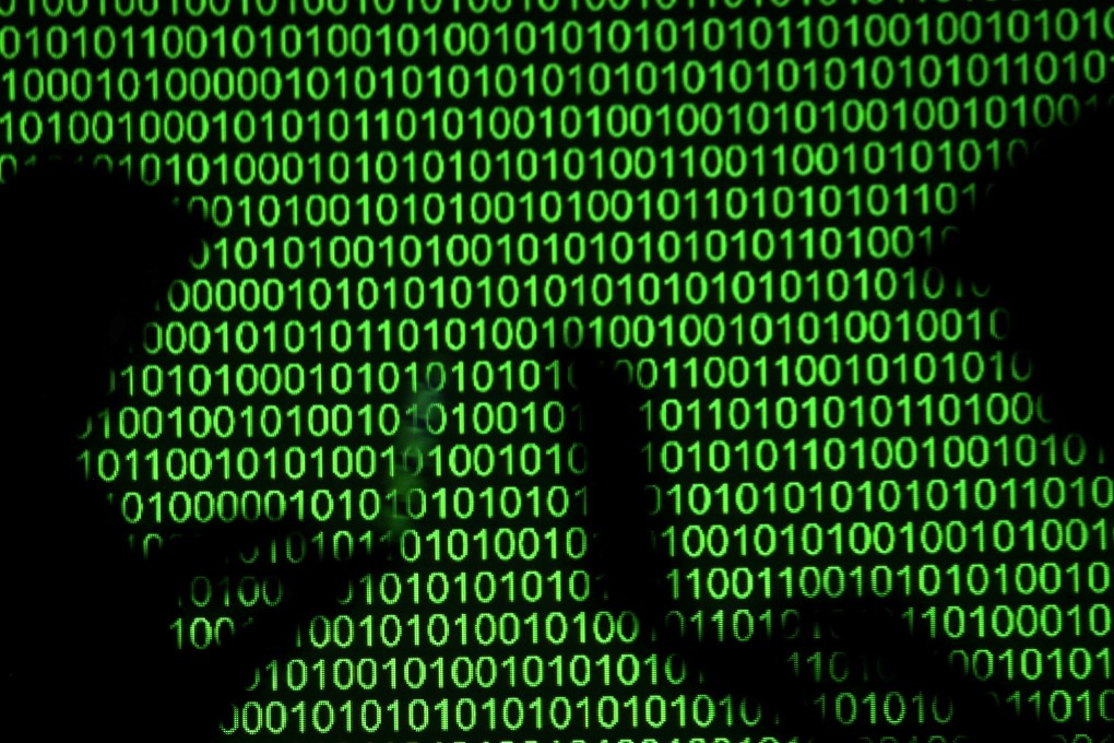 Silhouettes of laptop users next to a screen projection of binary code. Image: Reuters
