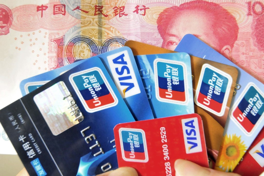 A Chinese woman poses with a handful of credit cards and a 100 yuan banknote Beijing . Photo: AFP