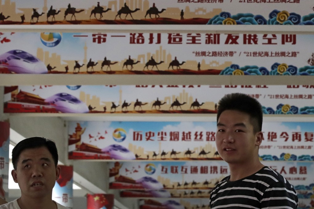 Workers stand in front of posters displaying slogans for Chinese President Xi Jinping's signature "China Dream" and "One Belt, One Road" foreign policy plans in June 2018. Photo: AP
