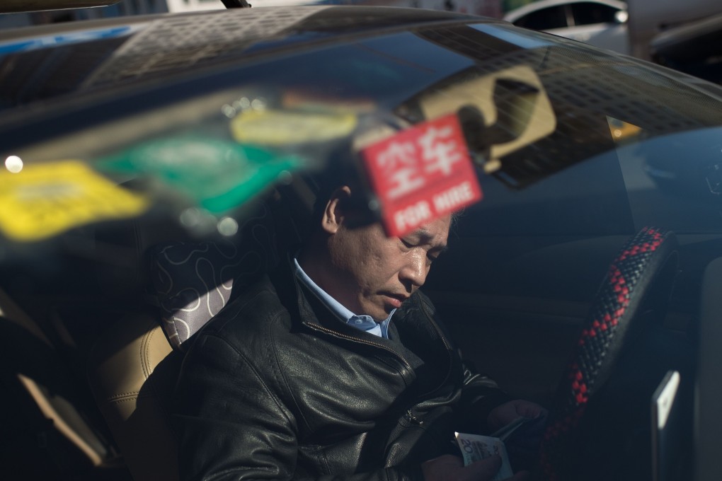 A taxi driver counts his money inside his car in Beijing on December 9, 2016. Photo: AFP