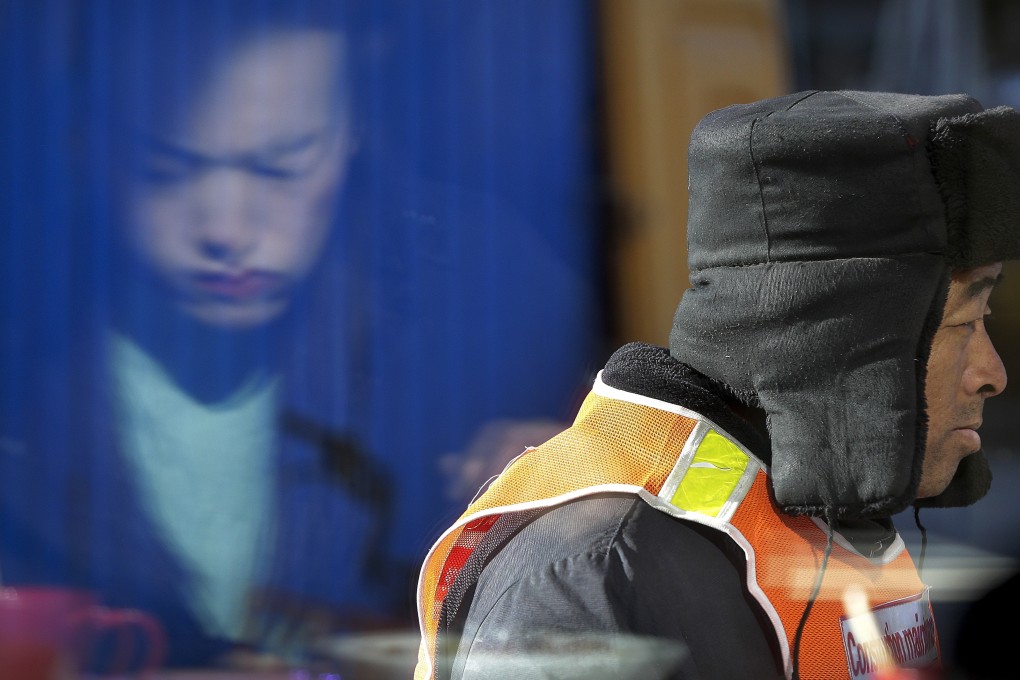 A construction worker walks by the reflection of a woman eating her lunch in Beijing. China has cut taxes and stepped up spending to help counter the country’s worst slowdown since the global financial crisis, amid a bruising trade war with the US. Photo: AP