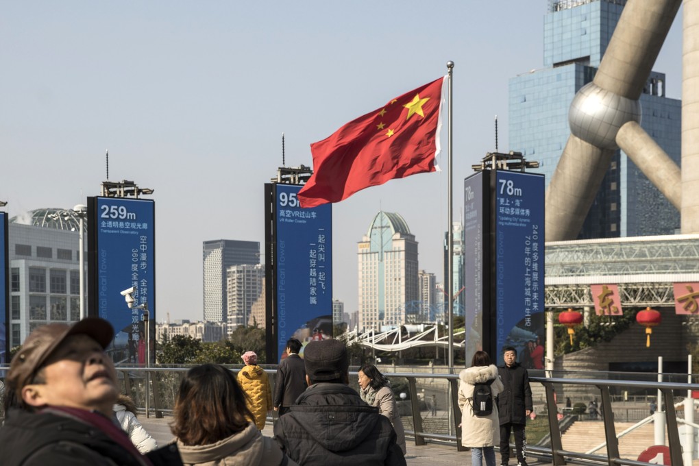 Pedestrians walk past a Chinese national flag on an elevated walkway in Shanghai, China, on December 28, 2018. Photo: Bloomberg