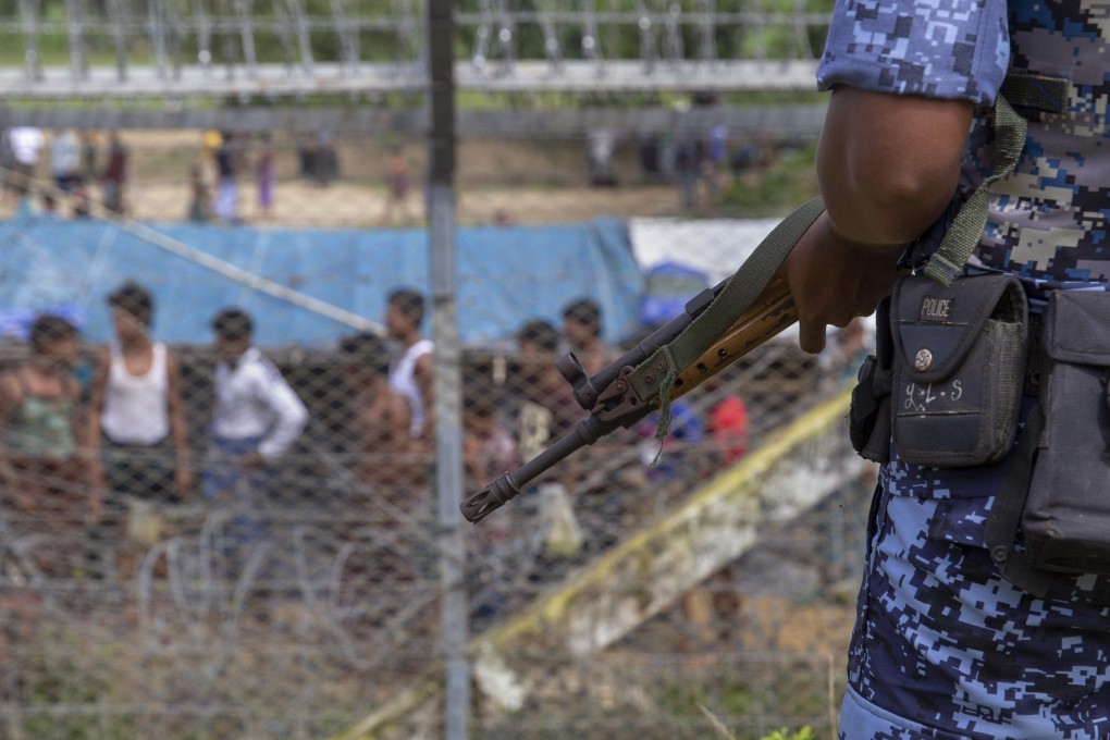 An August, 2018 photo of a Myanmar border guard by the fence in the ‘no man’s land’ between Myanmar and Bangladesh. Photo: AFP