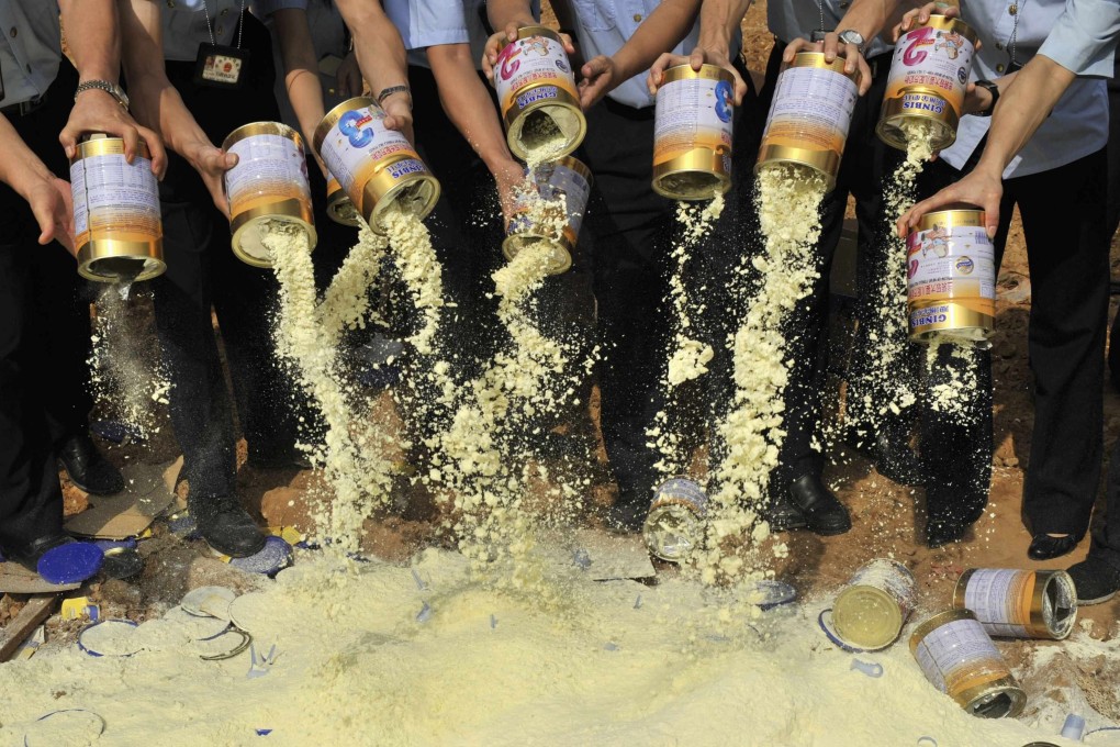 Tins of tainted milk powder are emptied at a dump site in Shenzhen in 2008. Photo: Reuters