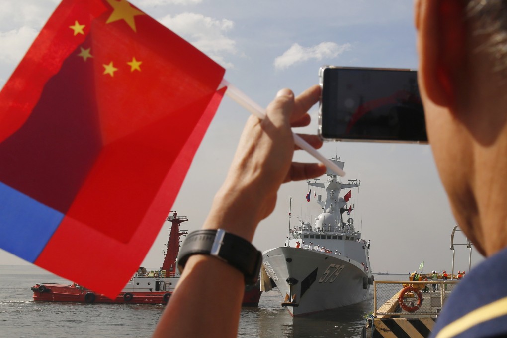 A welcome of Philippine and Chinese flags met the PLA Navy missile frigate Handan as it put in at Manila last week. Photo: AP