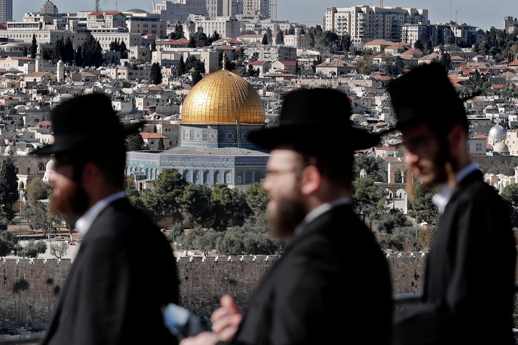 Orthodox Jews walk in the Mount of Olives area of the city of Jerusalem with the Dome of the Rock mosque in the background, on December 4, 2017. The influence of religious parties in Israeli politics has increased over the years. Photo: AFP