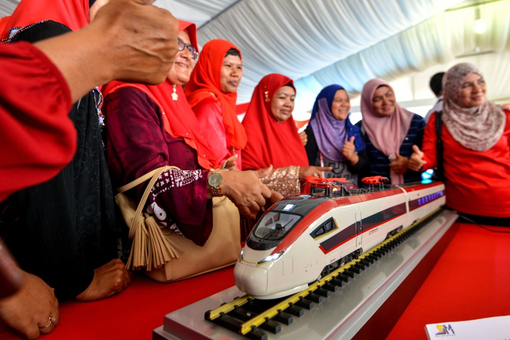People pose with a model train at the launch of the East Coast Rail Link project in Kuantan, Malaysia, in August 2017. Photo: Xinhua