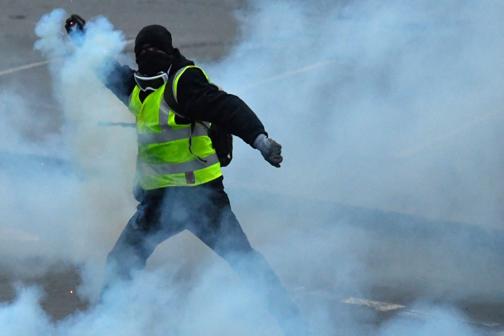 A protester throws back a tear-gas canister during an anti-government demonstration called the Yellow Vests “Gilets Jaunes” movement on January 26, 2019 in Quimper, western France. Photo: AFP