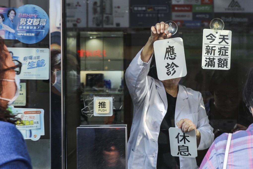 A member of staff puts up “off duty” and “daily visit limit reached” signs, as people queue up outside a clinic in Mong Kok for general check ups during the flu season, on January 17. Photo: Sam Tsang