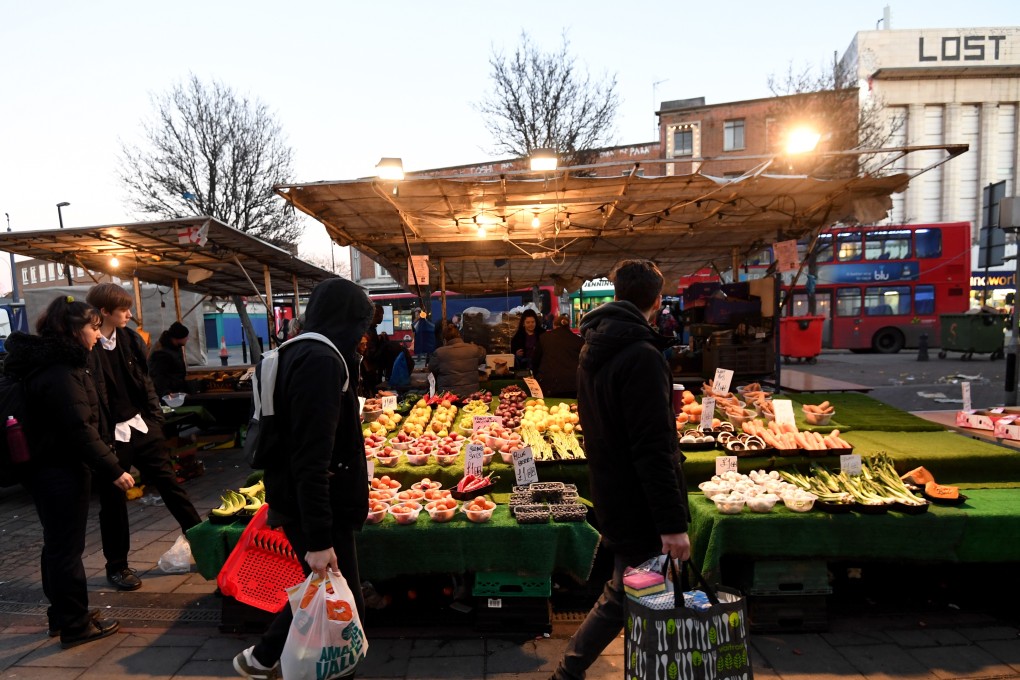 Shoppers walk by a vegetable stand at the Lewisham market in London on Monday. Photo: EPA-EFE