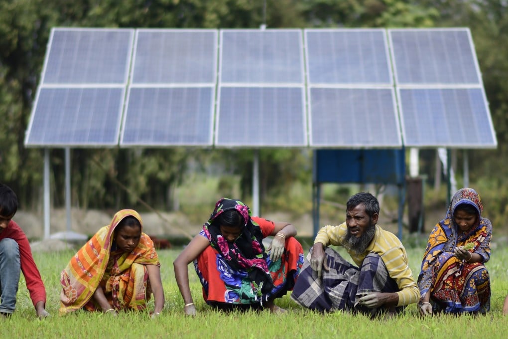 Indian farmers work near a newly installed water pump that relies on solar power. Photo: EPA