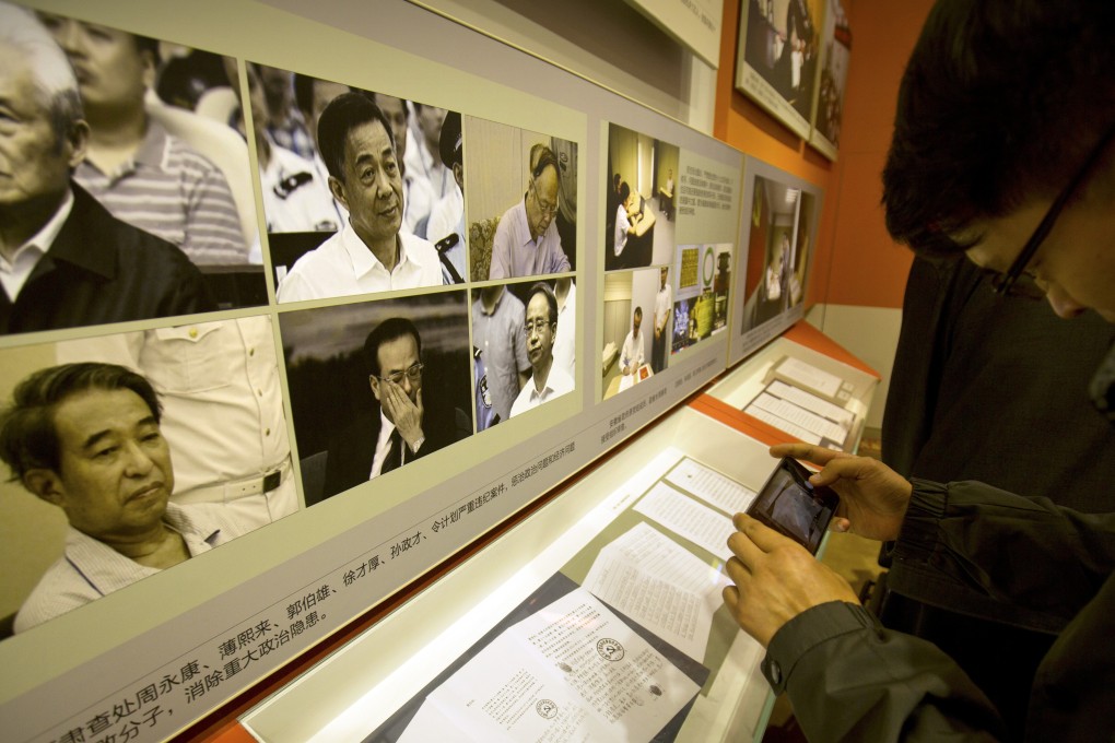 A visitor looks at photos of and statements of repentance by corrupt Chinese officials, (clockwise from upper left) Zhou Yongkang, Bo Xilai, Guo Boxiong, Ling Jihua, Sun Zhengcai and Xu Caihou, at an exhibition in Beijing on September 28, 2017. Photo: AP