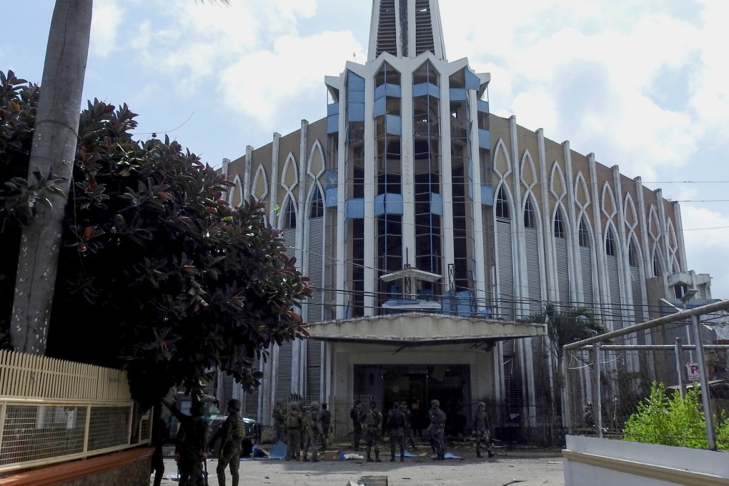 Policemen and soldiers are seen in front of the Catholic church in Jolo where the bombing took place. Photo: AFP