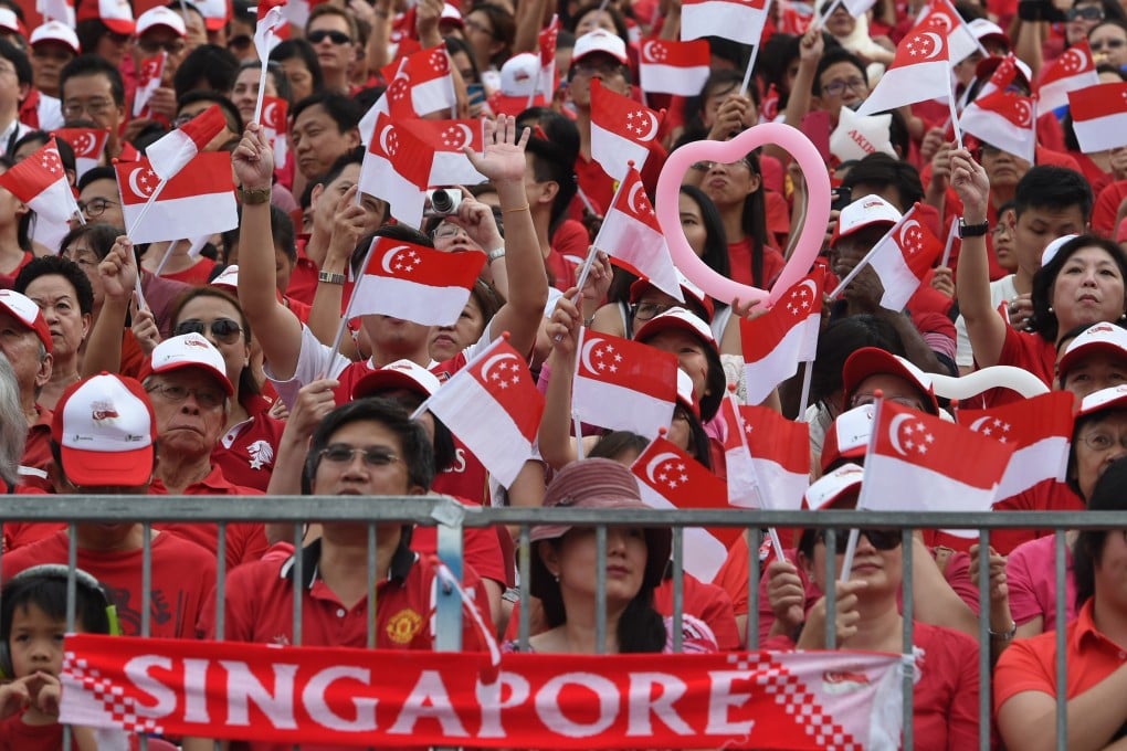 People wave flags during Singapore’s National Day celebrations. Picture: AFP