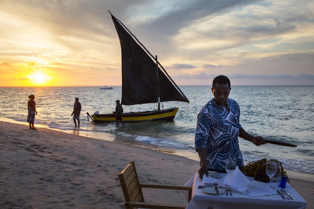 A butler from the Azura Benguerra Island resort sets the table for dinner as a fisherman brings up the dish of the day. Picture: Roger Borgelid
