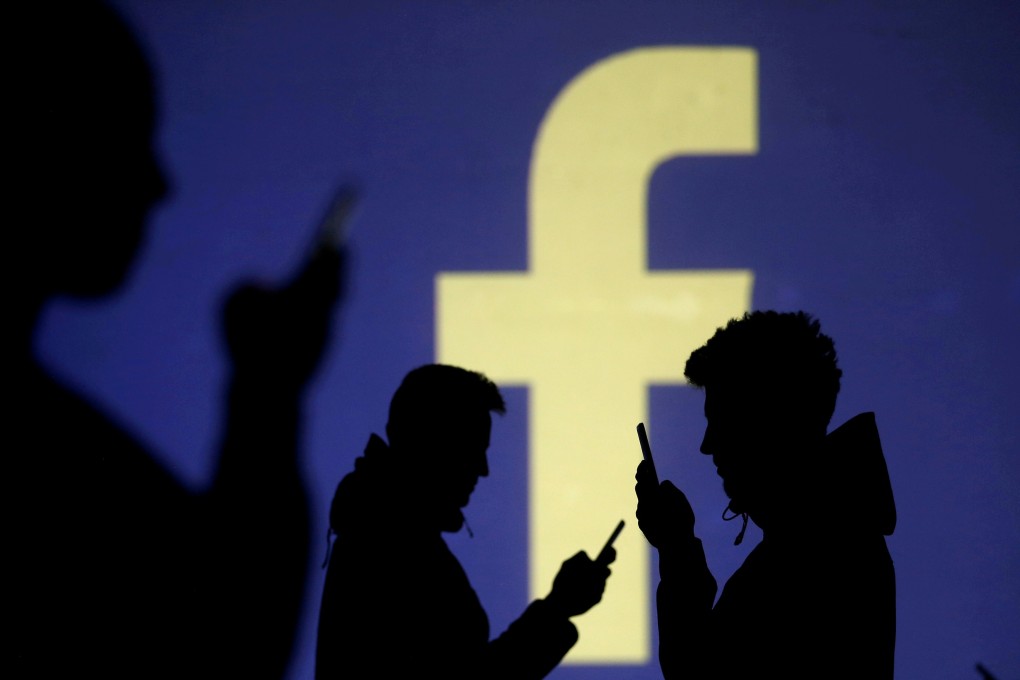 FILE PHOTO: Silhouettes of mobile users are seen next to a screen projection of Facebook logo in this picture illustration taken March 28, 2018. REUTERS/Dado Ruvic/Illustration/File Photo
