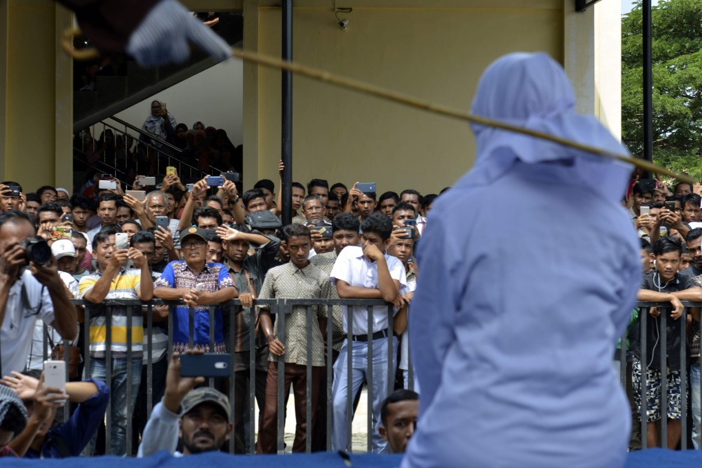 An 18-year-old Indonesian woman is caned in Banda Aceh as punishment for being caught cuddling with her boyfriend. Photo: AFP