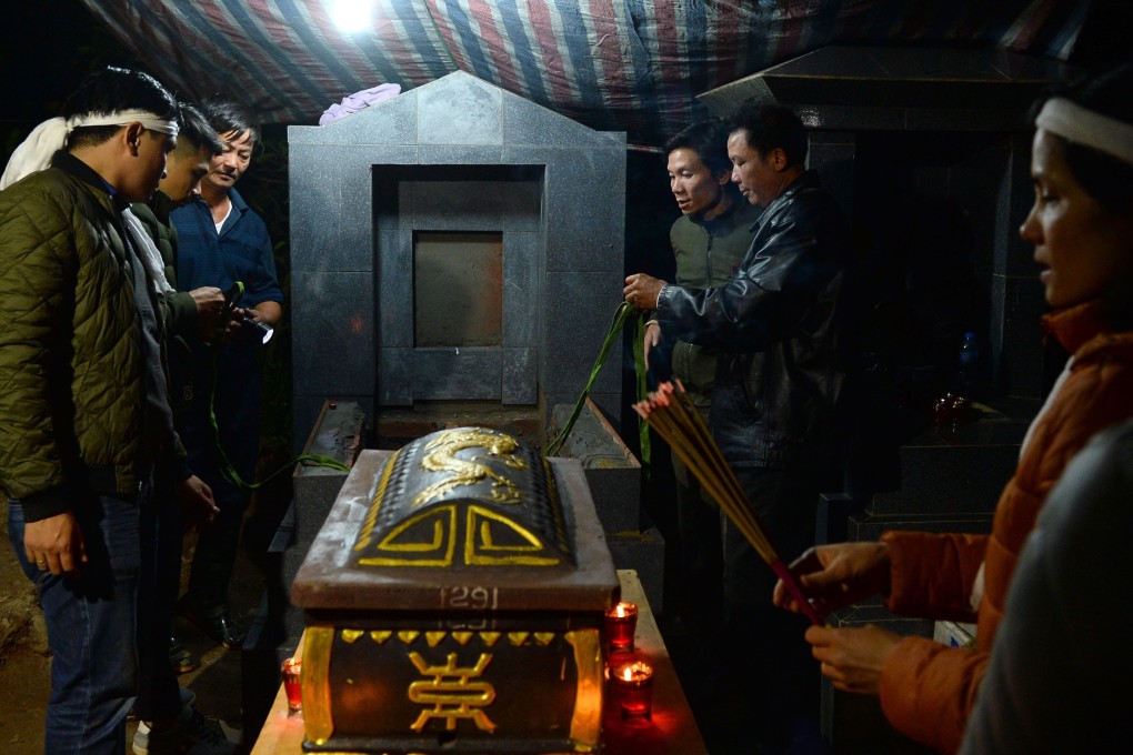 Relatives of the late Nguyen Van Thang praying before his new casket during a reburial ceremony on the outskirts of Hanoi. Photo: AFP