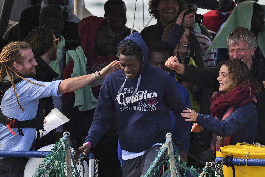 A migrant is cheered along as he disembarks from the rescue ship Sea-Watch 3, which was carrying 47 migrants, as it docked at the Sicilian port of Catania, southern Italy on Thursday. Europe's latest migrant stand-off came to a conclusion Thursday as 47 migrants kept at sea for nearly two weeks while Italy pressured European countries to take them in finally disembarked from their rescue ship in Sicily. Photo: AP Photo