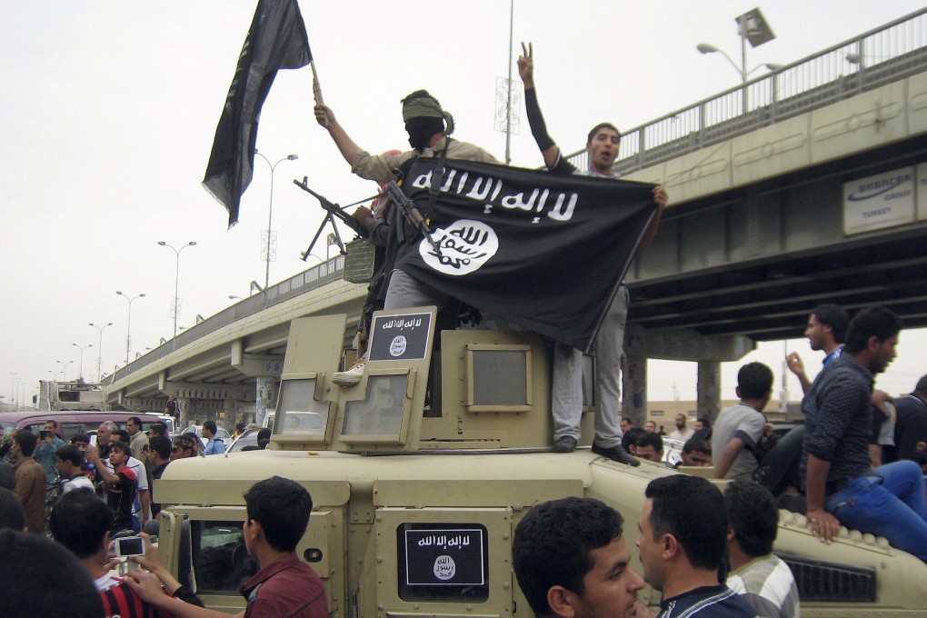 Islamic State group militants hold up their flag as they patrol in a commandeered Iraqi military vehicle in Fallujah, Iraq. Photo: AP