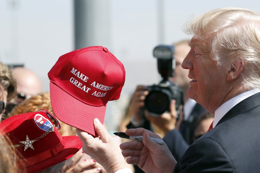 President Donald Trump hands a signed ‘Make America Great Again’ hat to a supporter. An award-winning cookbook author and California restaurant owner says anyone wearing the hats will be refused service at his restaurant. Photo: AP