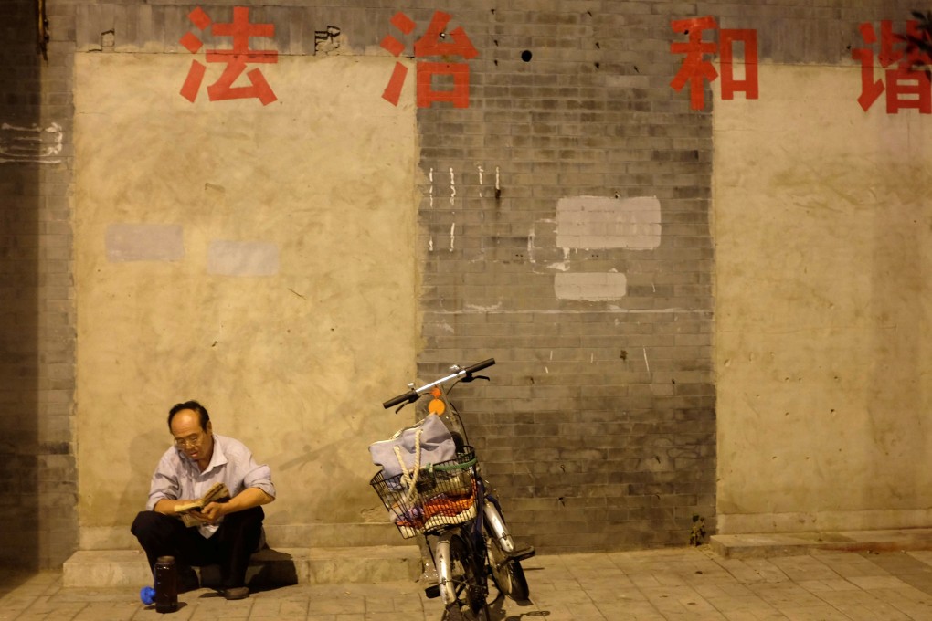 A man reads a book below political slogans reading “rule of law” and “harmony” in central Beijing. The education ministry has launched a review of all university constitutional law textbooks. Photo: Reuters