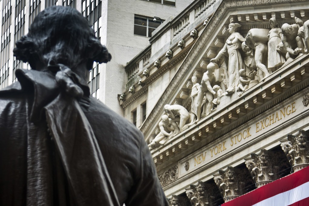 A statue of George Washington stands at Federal Hall near the flag-covered pillars of the New York Stock Exchange, in New York, July 2017. Photo: AP