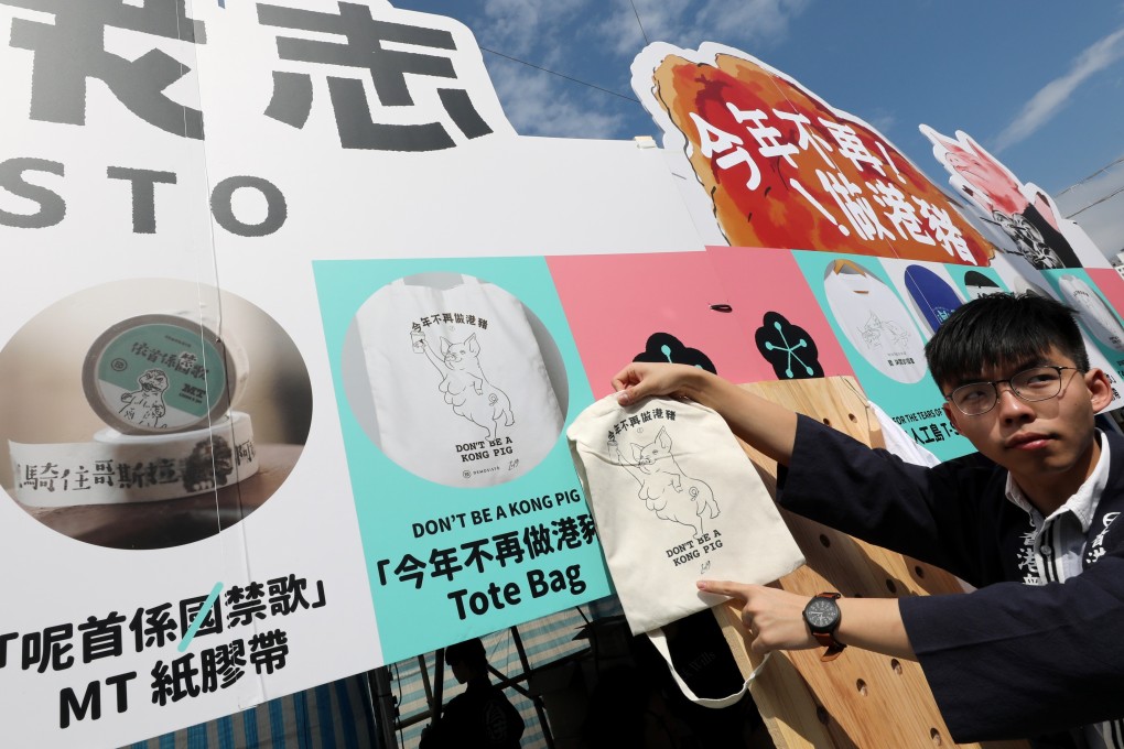 Activist Joshua Wong Chi-fung poses with a tote bag at the Demosisto stall in Victoria Park. Photo: Felix Wong