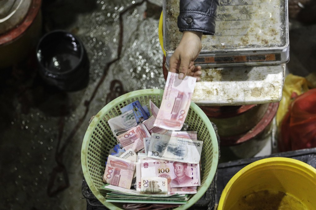 A 100 yuan banknote is placed into a basket at a food exhibition in Shanghai. As the Chinese economy weakens, the central bank is offering banks a carrot to extend more credit to small and medium-sized enterprises. Photo: Bloomberg