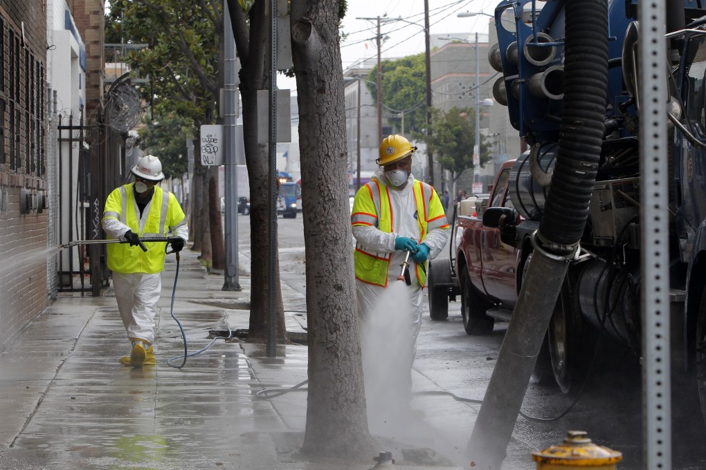 Sanitation workers in a protective suits clean a street in the heart of the Skid Row district in downtown Los Angeles. Photo: AP Photo