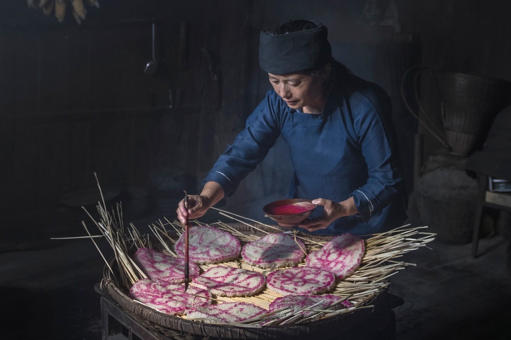 Detail from Drawing the Happiness by Ming Kai-chan Taken in Hunan Province in China. During the deep Autumn time, people were preparing food over the winter. A village woman was drawing the traditional symbols on the dried rice cake, hoping for a joyful and healthy coming year