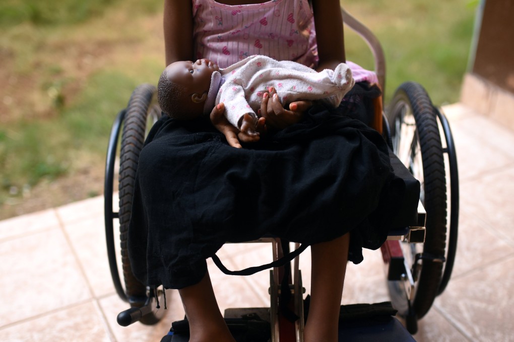 A five-year-old girl poses with her doll as she sits in her wheelchair in the courtyard of the Aberdeen Women's Centre, one year after a sexual assault that her family says left her paralysed. Photo: Reuters