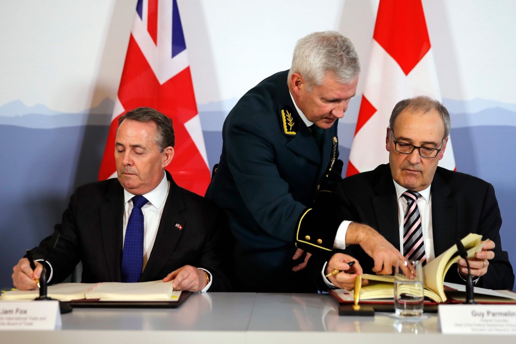 Britain’s International Trade Secretary Liam Fox (left) and Swiss Economic Minister Guy Parmelin (right) sign an agreement in Bern on February 11, 2019, to preserve trade relations between the two countries. Photo: AFP