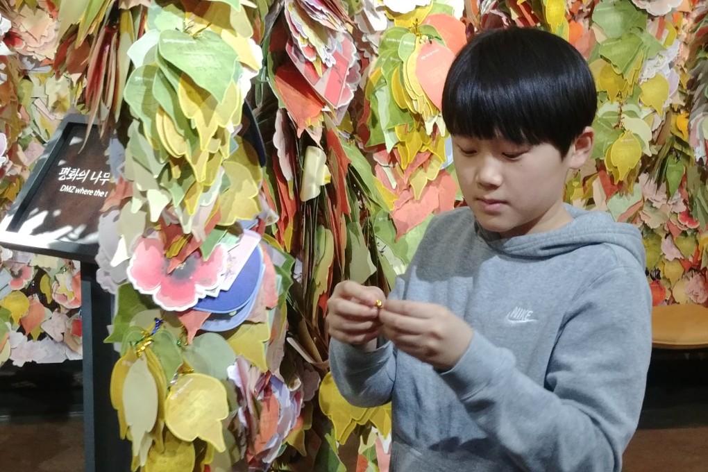 Kim Ki-tae hangs a message reading “Please help us reunify the fatherland” on the “Tree of Hope” at South Korea’s DMZ Museum. Photo: Park Chan-kyong