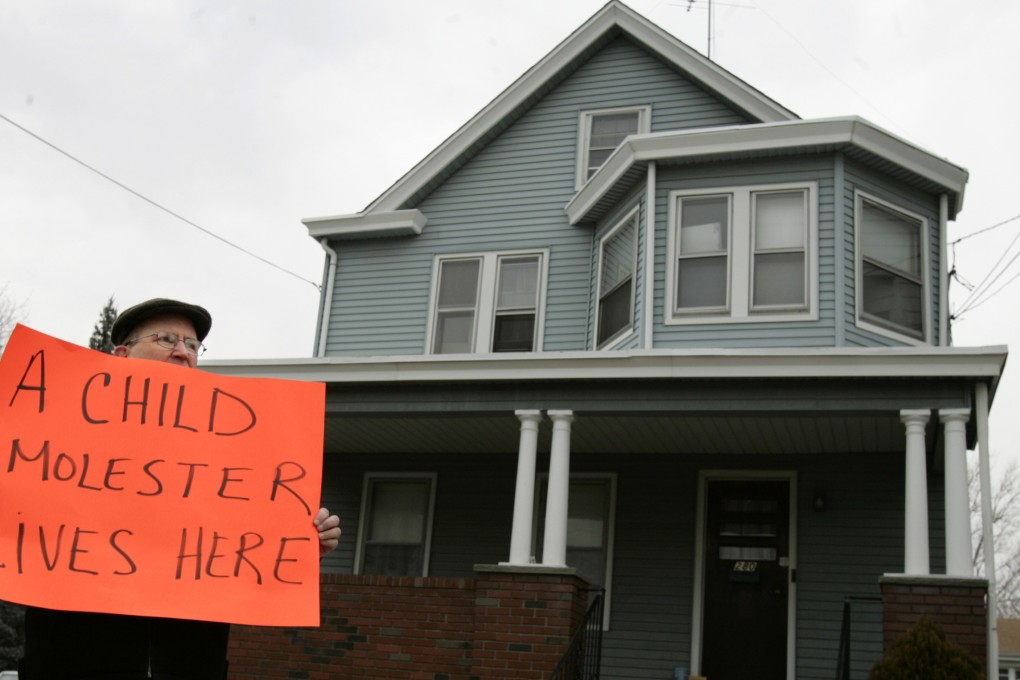 In this 2006 file photo, the Reverend Bob Holtson, a Catholic priest from West Orange, New Jersey, holds a sign identifying the house behind him as the home of former priest James Hanley in Paterson, New Jersey. On Wednesday, New Jersey's five Roman Catholic dioceses listed more than 180 clerics, including Hanley, who have been credibly accused of sexually abusing minors over a span of several decades. Photo: AP