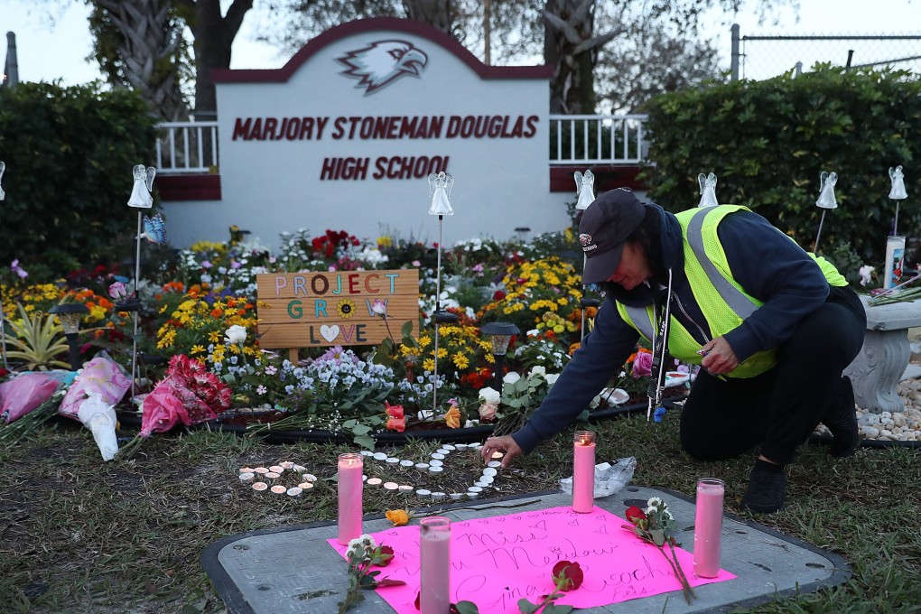 Wendy Behrend, a school crossing guard who was on duty one year ago when a shooter opened fire in Marjory Stoneman Douglas High School, pays her respects at a memorial to those killed on February 14, 2018, in Parkland, Florida. Photo: AFP