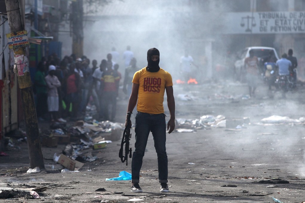 A man holds a weapon next to burning barricades during anti-government protests in Port-au-Prince, Haiti on February 17, 2019. Photo: Reuters