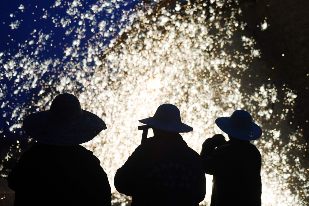 Blacksmiths watch the shower of sparks created by throwing molten metal against a cold stone wall in Nuanquan on Monday. Photo: AFP