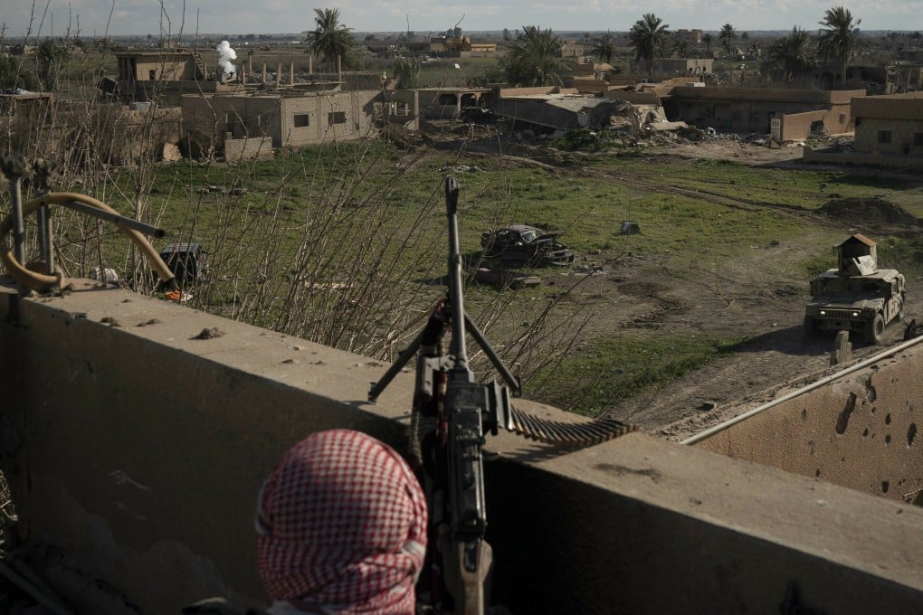 A US-backed Syrian Democratic Forces (SDF) fighter stands atop a building that overlooks the village where Islamic State militants in Baghouz are making their last stand. Photo: AP